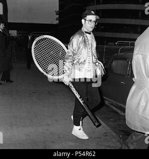 La photo d'Elton John à l'aéroport d'Heathrow, arrivant de l'Amérique, transportant un énorme raquette de tennis. 8 avril 1978. Banque D'Images