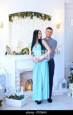 Woman wearing dress debout avec mari près de cheminée et l'arbre de Noël. Banque D'Images