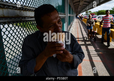 Brownsville, Texas, USA. 24 Juin, 2018. Un homme du nom de Ruben, nom d'Irène, qui a refusé de donner son nom de famille, partager un repas fourni par un groupe religieux qu'il attend sur le côté mexicain de la frontière des États-Unis il à demander asile. Plus tard, il a été admis. le long d'autres membres de la famille du Honduras. Credit : Miguel Juarez Lugo/ZUMA/Alamy Fil Live News Banque D'Images