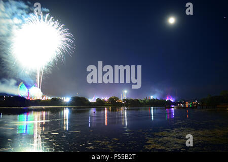 Newport, île de Wight, au Royaume-Uni. 24 Juin, 2018. D'artifice et un près de la pleine lune annoncer la fin de la dernière journée de l'île de Wight Festival dans la nuit de dimanche la garniture de la bande 'Les tueurs' jouer sur la scène principale, vu dans la distance dans des lumières bleues. Photographie prise du bord de la rivière Medina à Newport, Isle of Wight, 24 juin 2018. Crédit : Matthieu Blythe/Alamy Live News Banque D'Images