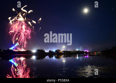 Newport, île de Wight, au Royaume-Uni. 24 Juin, 2018. D'artifice et un près de la pleine lune annoncer la fin de la dernière journée de l'île de Wight Festival dans la nuit de dimanche la garniture de la bande 'Les tueurs' jouer sur la scène principale, vu dans la distance dans des lumières bleues. Photographie prise du bord de la rivière Medina à Newport, Isle of Wight, 24 juin 2018. Crédit : Matthieu Blythe/Alamy Live News Banque D'Images