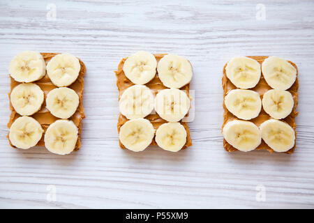 Vegan toasts avec beurre d'arachide et banane sur un fond en bois blanc, par le dessus. Banque D'Images