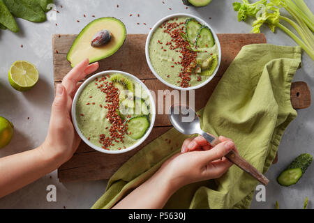 Bol à smoothie vert kiwi frais, les flaxseeds, concombre et d'avocat dans les mains Banque D'Images