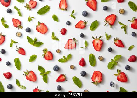 Motif de fruits avec la moitié de fraises, bleuets et de feuilles de menthe sur un fond blanc, vue du dessus Banque D'Images