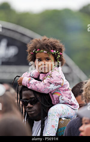 Gorgeous mixed race baby girl sitting sur les épaules d'un adulte à l'Afrique 2018 Oye music festival à Sefton Park, Liverpool. Banque D'Images