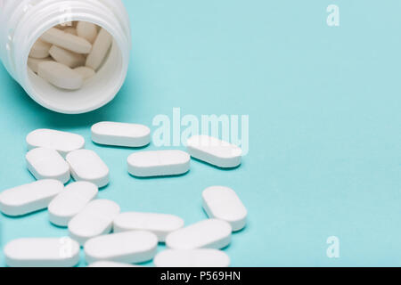 Flacon de médicaments et pilules blanches renversé sur fond de couleur bleu pastel. Médicaments et prescription pills arrière-plan. Les médicaments pharmaceutiques. Banque D'Images