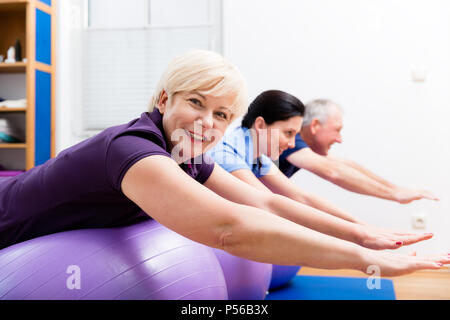 Couple Physio montrant comment utiliser ballon de gymnastique pour des exercices Banque D'Images