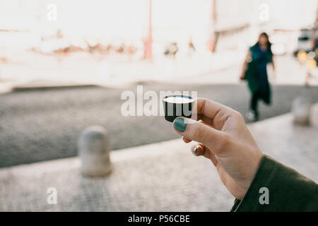 A woman's hand est titulaire d'un verre de chocolat dans laquelle la liqueur traditionnelle portugaise est teinté nommé Ginjinha et préparer à boire Banque D'Images