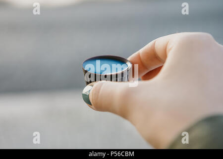 A woman's hand est titulaire d'un verre de chocolat dans laquelle la liqueur traditionnelle portugaise est teinté nommé Ginjinha et préparer à boire Banque D'Images