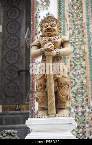 Statue de gardien sur le terrain du Palais Royal à Bangkok, Thaïlande. La mosaïque colorée en pierre ornée peut être vue sur le mur derrière la figure. Banque D'Images