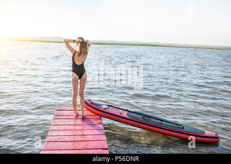 Femme avec paddleboard sur la jetée à l'extérieur Banque D'Images