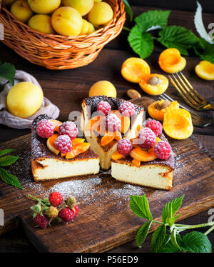 Morceaux de Tarte au fromage cottage avec des fraises et d'abricots sur une planche de bois brun, vue du dessus Banque D'Images