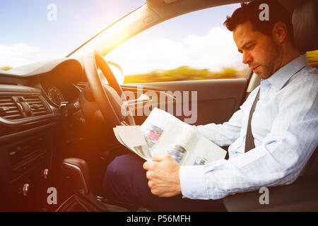 Homme assis dans la voiture et la lecture de news paper Banque D'Images