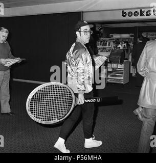 La photo d'Elton John à l'aéroport d'Heathrow, arrivant de l'Amérique, transportant un énorme raquette de tennis. 8 avril 1978. Banque D'Images