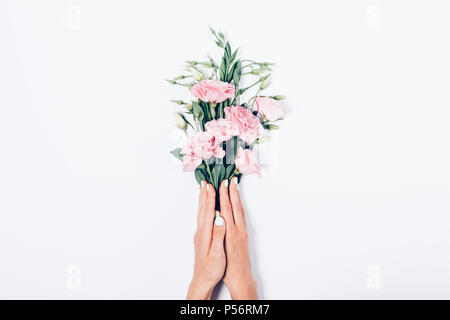 Woman's hands holding manucure avec des tas de fleurs roses sur fond blanc, vue du dessus. Fleuriste composition mise à plat faisant un bouquet de beaut Banque D'Images