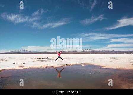 Heureux de sauter sur le côté d'une flaque d'eau salée naturelle au Salar de Uyuni, Bolivie. Banque D'Images