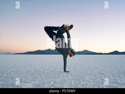 Boy doing handstand un bras pendant le coucher du soleil. Salar de Uyuni (salines), la Bolivie. Mode de vie actif, danse, fitness, aventure. Jun 2018 Banque D'Images