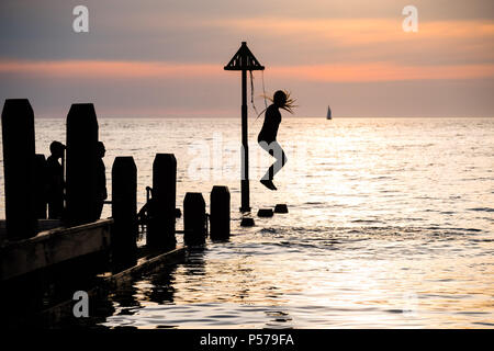 25 juin 2018 . Pays de Galles Aberystwyth UK UK Weather : un groupe de jeunes gens en silhouette sauter dans la mer au large de la jetée sur la plage d'Aberystwyth au crépuscule à la fin d'une autre belle journée de soleil ininterrompues à chaud. Le Royaume-Uni est dans une mini canicule, avec des températures prévues pour frapper 29º ou 30º Celsius par le milieu de la semaine Photo © Keith Morris Crédit : Keith morris/Alamy Live News Banque D'Images