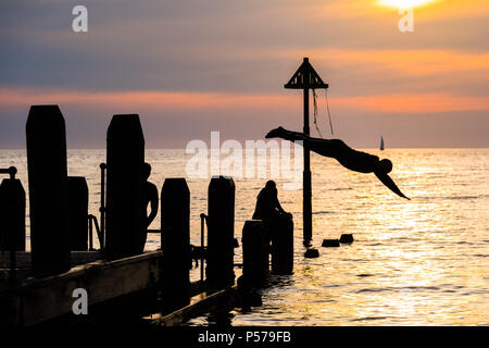 25 juin 2018 . Pays de Galles Aberystwyth UK UK Weather : un groupe de jeunes gens en silhouette sauter dans la mer au large de la jetée sur la plage d'Aberystwyth au crépuscule à la fin d'une autre belle journée de soleil ininterrompues à chaud. Le Royaume-Uni est dans une mini canicule, avec des températures prévues pour frapper 29º ou 30º Celsius par le milieu de la semaine Photo © Keith Morris Crédit : Keith morris/Alamy Live News Banque D'Images