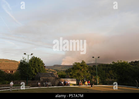 Tameside, UK. 25 Juin, 2018. Les quilleurs à Dobcross Band Club continuent de se faire concurrence, tandis qu'un feu brûle dans la lande de distance. Credit : James Grady/Alamy Live News Banque D'Images