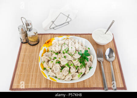 Fédération de quenelles avec les herbes et les oignons. Raviolis de viande. Le plat est servi dans une assiette. Servi avec des boulettes est la crème dans un bol. Banque D'Images