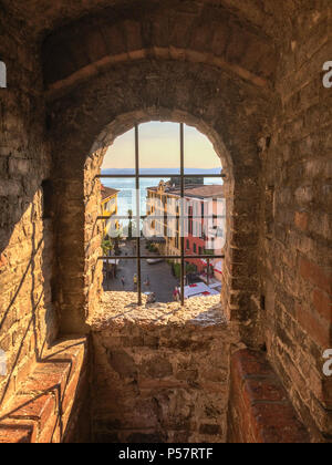 Vue à travers une fenêtre avec des barres de treillis de château dans la ville de Sirmione sur le lac de Garde Banque D'Images