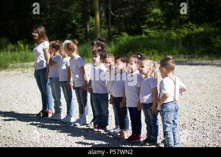 Groupe des petits enfants différents âges sont alignées en ligne dans parc d'été Banque D'Images