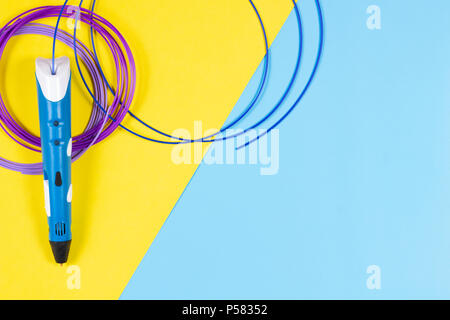 Stylo 3d avec des filaments de plastique en couleur sur fond jaune et bleu. Banque D'Images