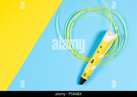 Stylo 3d avec des filaments de plastique en couleur sur fond jaune et bleu. Banque D'Images