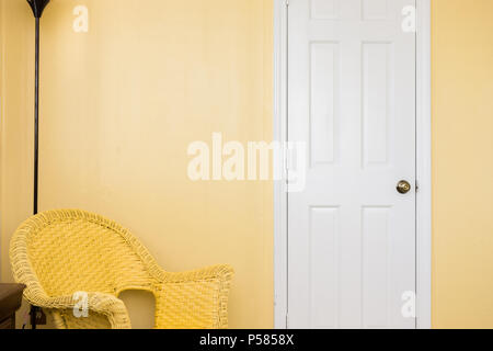 Nettoyer porte blanche, jaune chaise et lampe en coin, des murs en bois jaune Banque D'Images