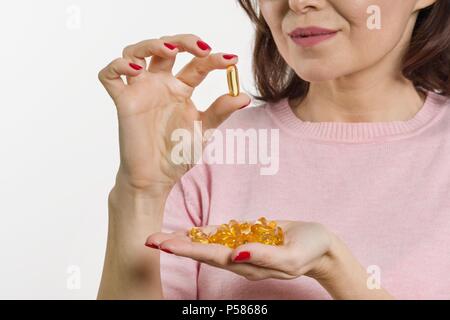 Femme est titulaire d'une capsule de vitamine E, l'huile de poisson. fond blanc, l'accent sur la capsule Banque D'Images