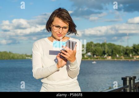 Femme d'une grande fait un appel important et regarde la carte de visite. Banque D'Images