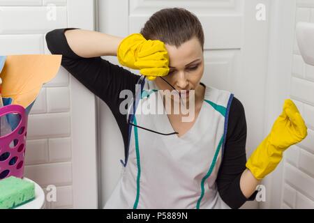 Tired woman sitting on salle de bains marbre avec des produits de nettoyage et d'équipement. Banque D'Images