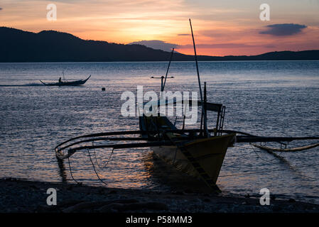 Banca traditionnel bateau sur la rive au coucher du soleil, Anilao, Philippines Banque D'Images