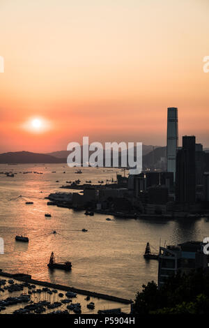 Vue imprenable sur le coucher du soleil au-dessus du port Victoria à Hong Kong avec le gratte-ciel de Kowloon Tsim Sha Accueil front de mer dans la gauche en Chine Banque D'Images