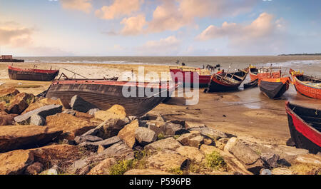 Indien de bois bateaux de pêche amarrés dans l'Orissa creek côtière au coucher du soleil en attente de la marée haute mer. Banque D'Images