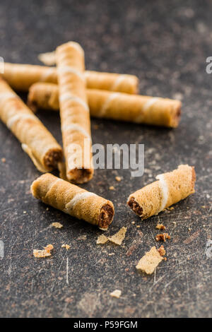 Rouleaux de gaufrettes au chocolat sucré sur la vieille table de cuisine. Banque D'Images