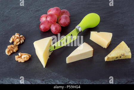 Assiette de fromages fromages différents avec des raisins et noix sur la plaque en ardoise noire.vue d'en haut Banque D'Images