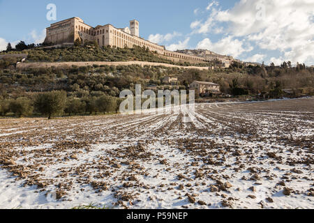 Sur assise ville (Ombrie) en hiver, avec une route de campagne couverte de neige et un ciel bleu avec des nuages blancs Banque D'Images