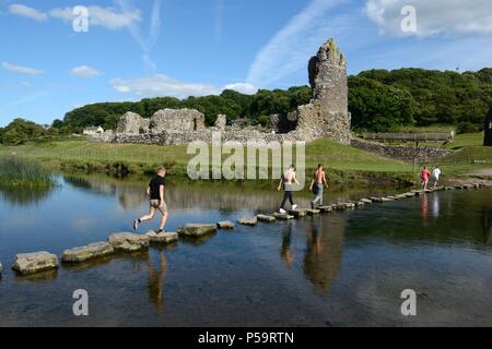 Les gens en utilisant de vieilles pierres de gué pour traverser la rivière Ewenny au château de Ogmore par mer de Ogmore Glamorgan Wales Cymru UK Banque D'Images