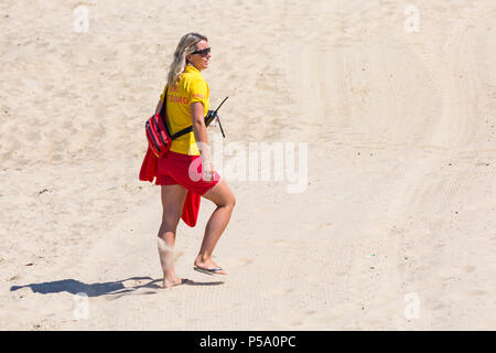 Bournemouth, Dorset, UK. 26 juin 2018. Météo France : sunseekers tête à la plages de Bournemouth sur un autre beau jour ensoleillé chaud avec un ciel bleu et soleil ininterrompue, à la hausse des températures à la mer. Sauveteur RNLI marchant sur le sable. Credit : Carolyn Jenkins/Alamy Live News Banque D'Images