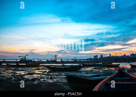 Silhouette de bateaux de pêche à marée basse, le coucher du soleil près de Mahim bay - Mumbai, Maharashtra, Inde. Et Worli Link, Bandra Pali Hill dans l'arrière-plan. Banque D'Images