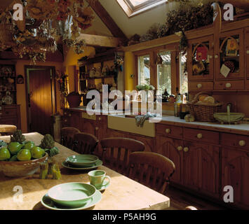 Les plaques vertes et tasses sur la table de cuisine en pin pays EXTENSION avec placards en pin évier en céramique blanc et Banque D'Images