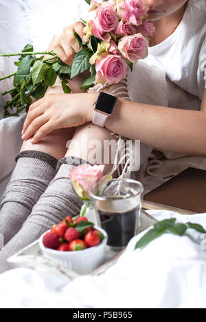 Petit-déjeuner romantique au lit. Un bouquet de roses parfumées et un café du matin. Fraises fraîches. Bon matin, dans le lit froissé. Vous pourrez vous détendre. Copy space Banque D'Images