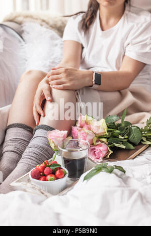 Petit-déjeuner romantique au lit. Un bouquet de roses parfumées et un café du matin. Fraises fraîches. Bon matin, dans le lit froissé. Vous pourrez vous détendre. Copy space Banque D'Images