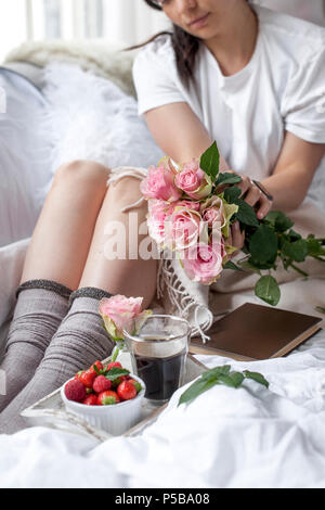 Petit-déjeuner romantique au lit. Un bouquet de roses parfumées et un café du matin. Fraises fraîches. Bon matin, dans le lit froissé. Vous pourrez vous détendre. Copy space Banque D'Images