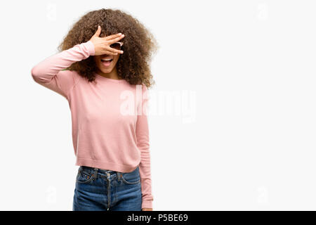 African American Woman wearing orange sunglasses peeking sous le choc couvrant le visage et les yeux avec la main, regardant à travers les doigts avec embarrassé d'expression. Banque D'Images