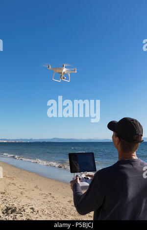 DJI Phantom 4 drone avec appareil photo en vol au dessus de la mer et sous le contrôle de l'opérateur. Côtes du Maroc en arrière-plan. Banque D'Images