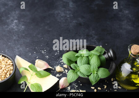 Les feuilles de basilic, de parmesan et d'autres ingrédients de la sauce pesto sur noir Banque D'Images