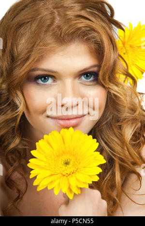 La rousse très jolie jeune femme aux yeux bleus avec des fleurs jaunes, sourire, portrait vertical Banque D'Images